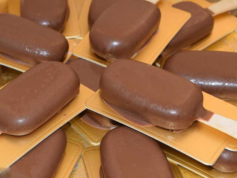 Luscious chocolate-covered ice cream on a stick with drips.